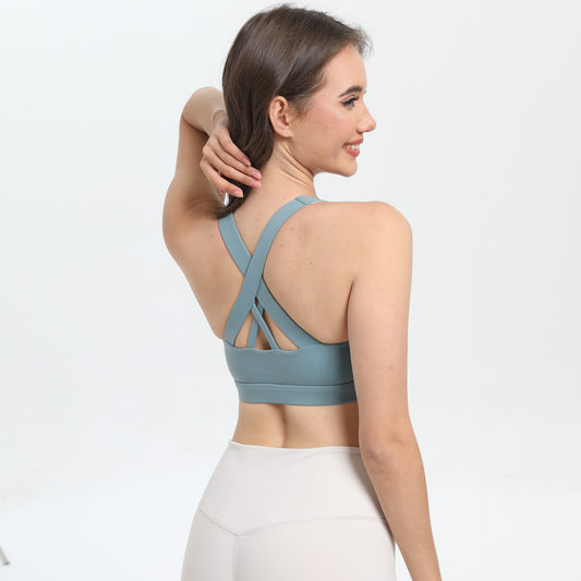 Woman wearing a blue sports bra and white leggings on a light gray background
