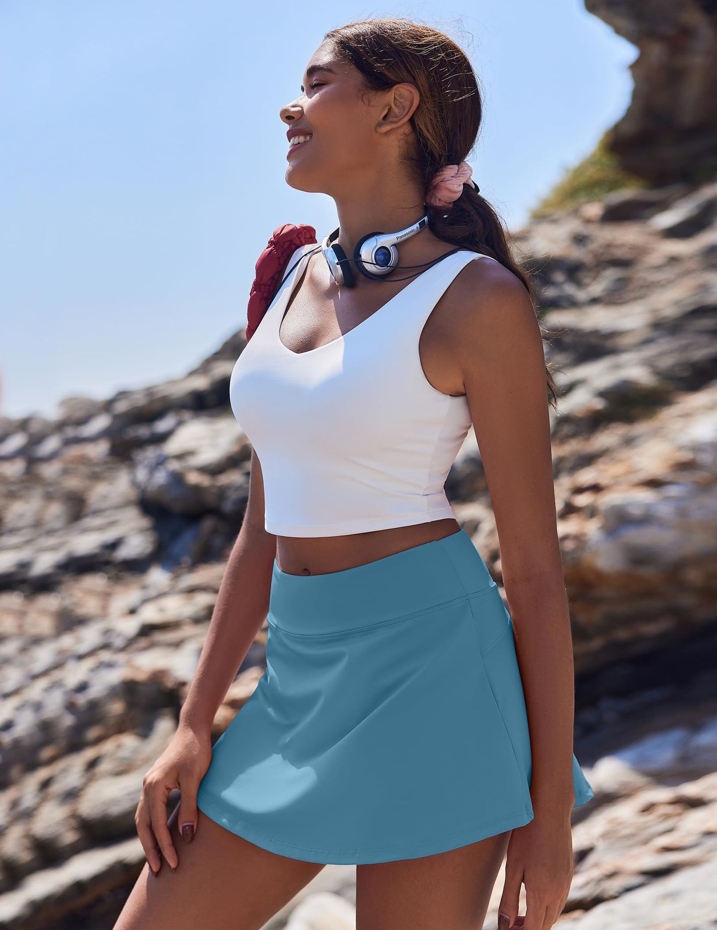 girl with blue skort and white top standing on rocks