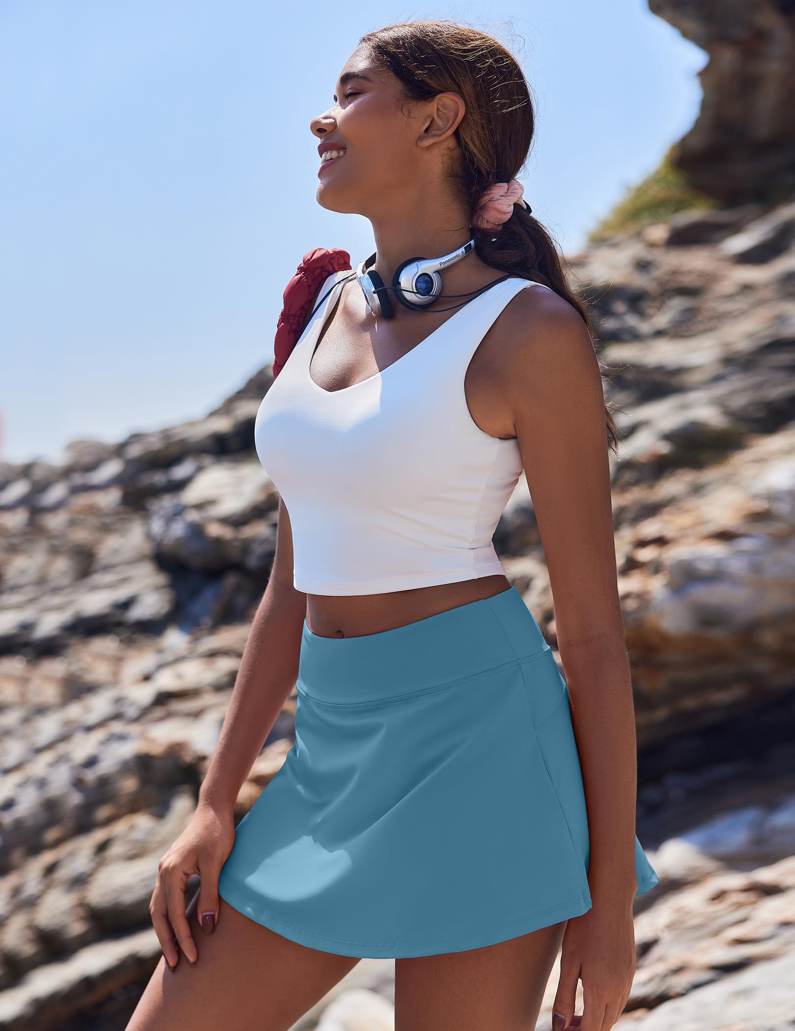 girl with blue skort and white top standing on rocks