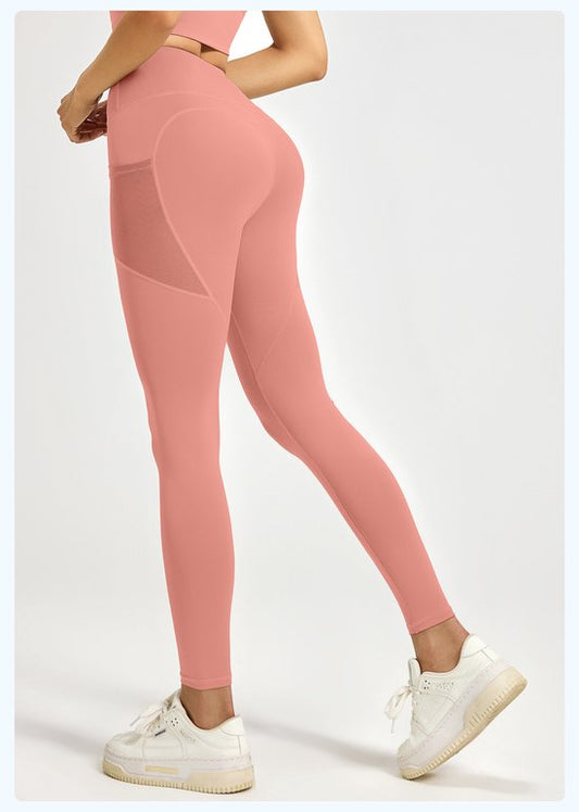 Pink leggings with mesh panels worn by a person on a white background