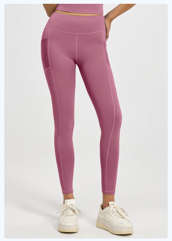 Person wearing dark pink leggings and white sneakers on a light gray background