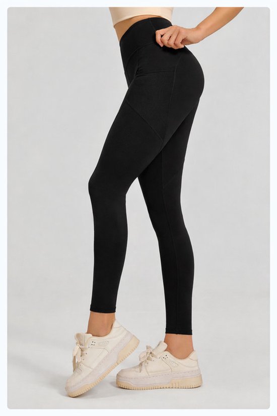 Person wearing black leggings with beige sneakers on a light gray background