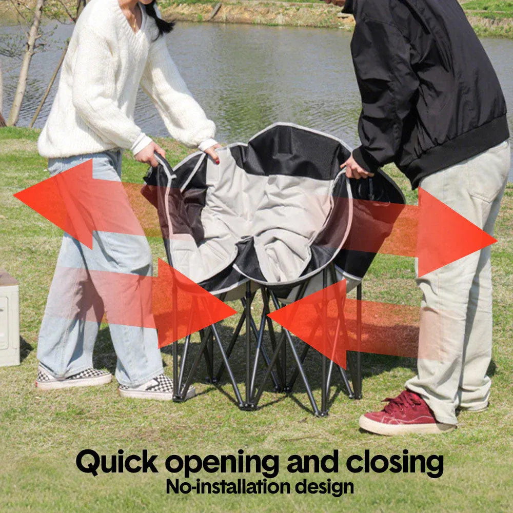 Two people setting up a folding chair outdoors near a body of water.